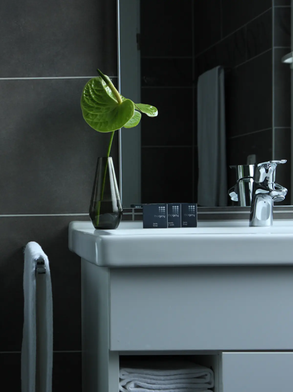 Modernes Badezimmer mit dunklen Fliesen und Pflegeprodukten